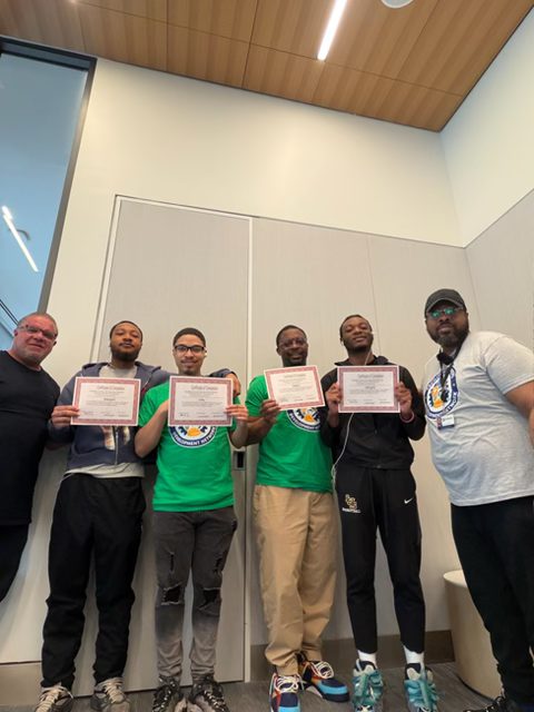 Trainees and instructors holding up their certificates of completion